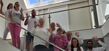 Betreuungsteam von Liebevolle Betreuung 24 bei interner Schulung, freundlich winkend im modernen Gebäude